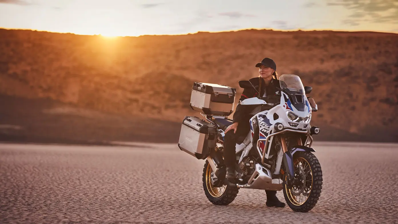 Fotómodell ül egy CRF1100L Africa Twin motorkerékpáron a sivatagban.